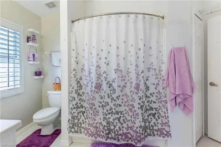 Bathroom featuring curtained shower, tile patterned floors, and toilet