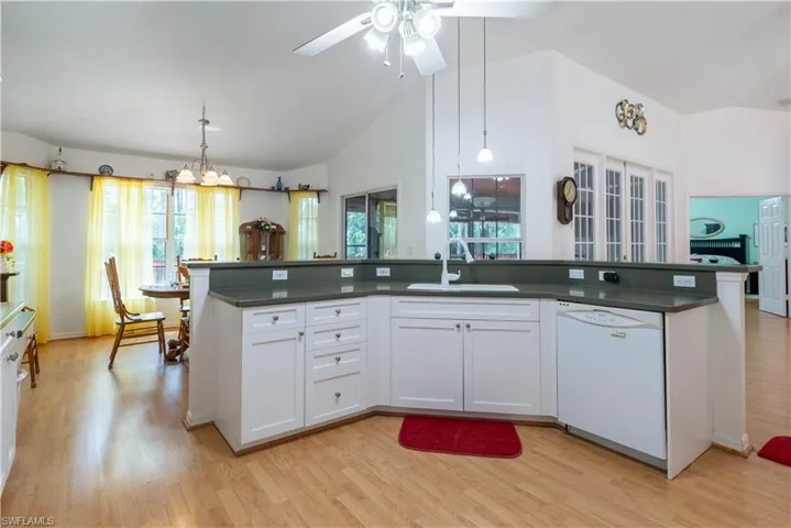 Kitchen with white cabinetry, decorative light fixtures, white dishwasher, sink, and light hardwood / wood-style floors