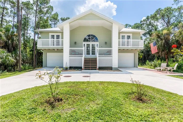 Beach home with a garage, a front lawn, french doors, and a porch