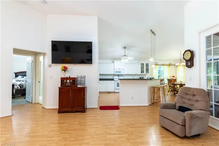 Living room with high vaulted ceiling, ceiling fan, and light hardwood / wood-style flooring