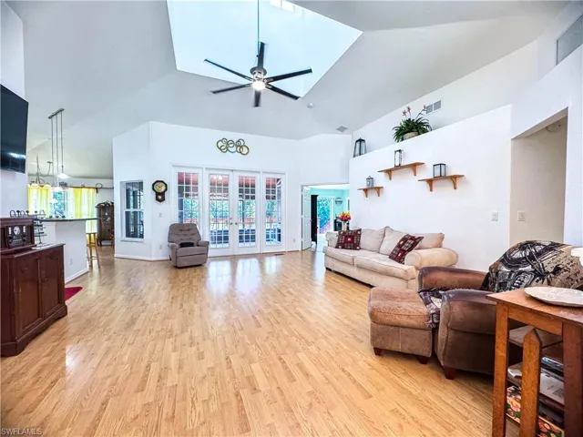 Living room featuring high vaulted ceiling, french doors, ceiling fan, and light hardwood / wood-style flooring
