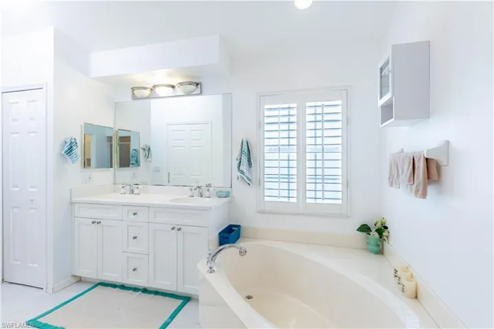 Bathroom featuring vanity, a tub to relax in, and tile patterned floors