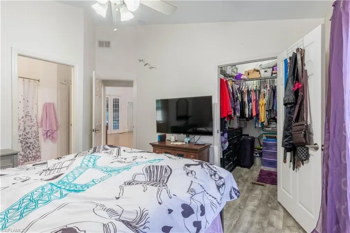 Bedroom featuring a closet, light wood-type flooring, lofted ceiling, and ceiling fan