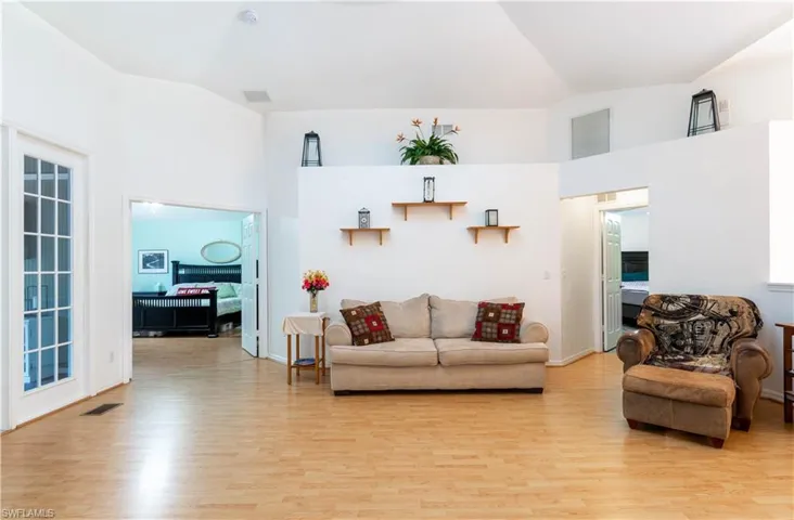 Living room with high vaulted ceiling and light hardwood / wood-style floors