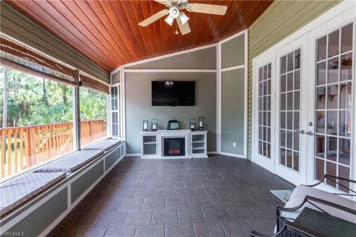 Unfurnished sunroom featuring wooden ceiling, ceiling fan, a fireplace, and lofted ceiling