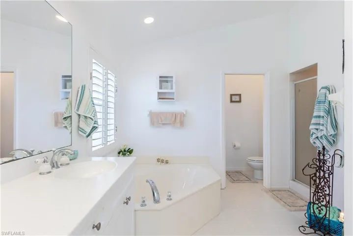 Full bathroom featuring vanity, toilet, lofted ceiling, and shower with separate bathtub