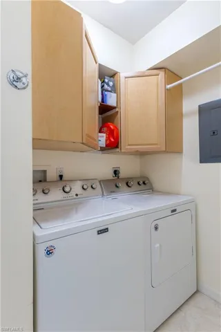 Washroom featuring electric panel, cabinets, and independent washer and dryer