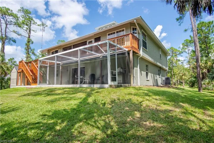 Back of property featuring a sunroom, central AC, and a yard