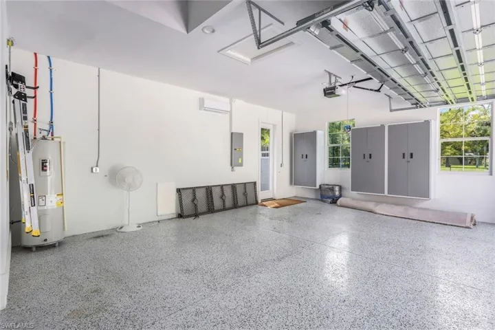 Garage featuring a wall mounted AC, a garage door opener, and electric water heater