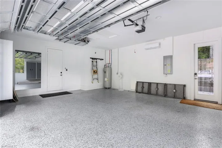 Garage featuring a garage door opener and electric water heater