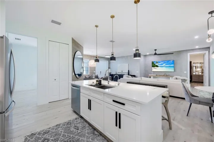 Kitchen featuring light hardwood / wood-style flooring, stainless steel appliances, hanging light fixtures, a kitchen island with sink, and sink