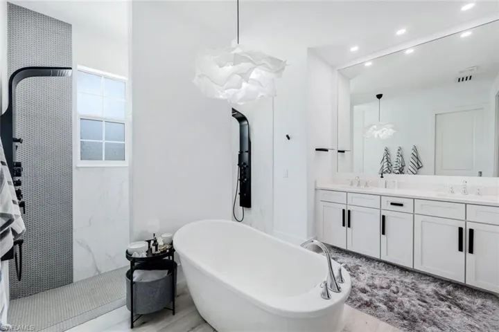 Bathroom featuring dual vanity and a tub