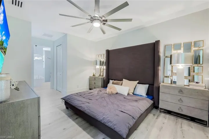 Bedroom with a closet, ceiling fan, ensuite bath, and light hardwood / wood-style flooring