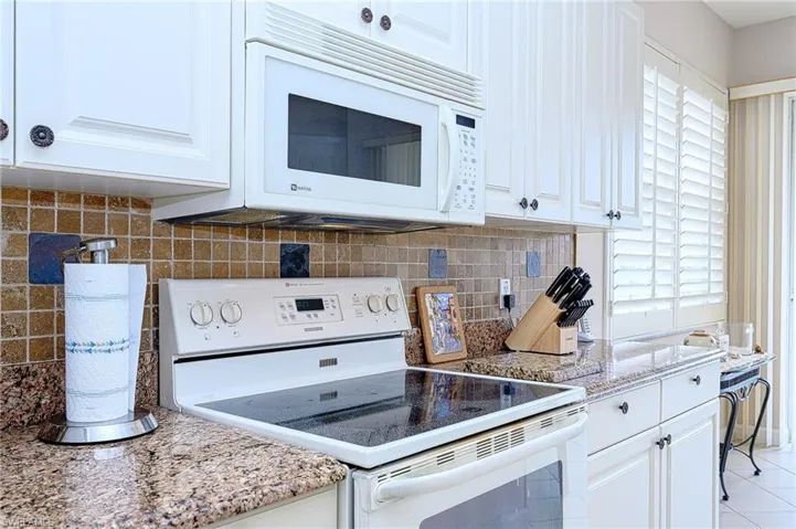 Kitchen featuring white cabinetry, light tile patterned floors, and white appliances