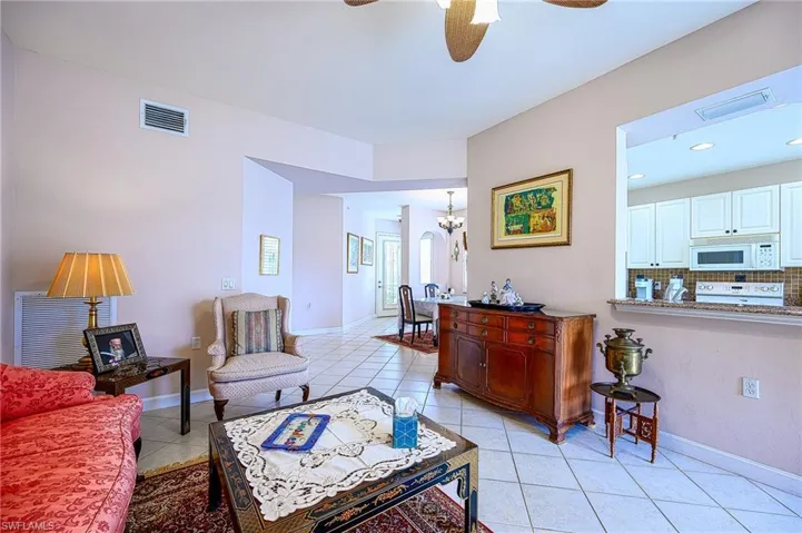 Tiled living room with ceiling fan with notable chandelier
