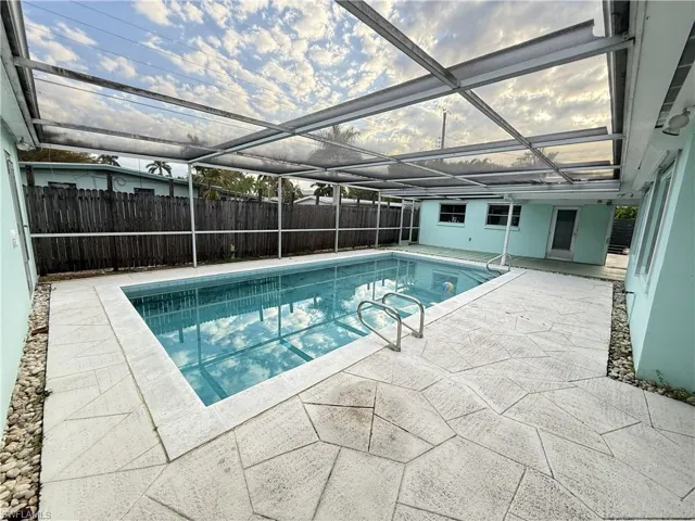 View of pool with a sunroom, patio surround, a lanai, and a fenced backyard