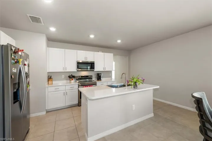 Kitchen featuring light countertops, white cabinetry, visible vents, appliances with stainless steel finishes, and a sink