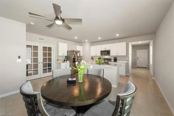 Dining room with light tile patterned floors, baseboards, ceiling fan, recessed lighting, and french doors
