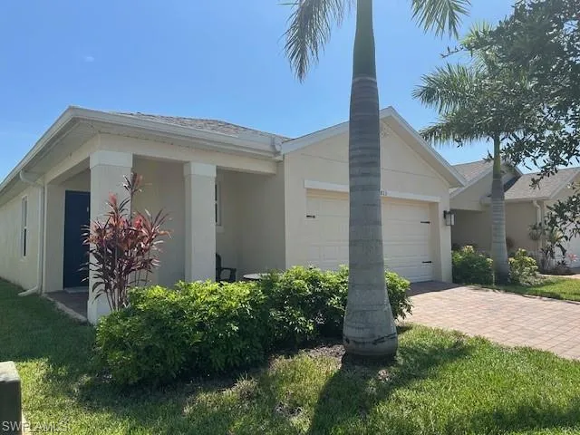 Ranch-style home with a garage, stucco siding, and decorative driveway