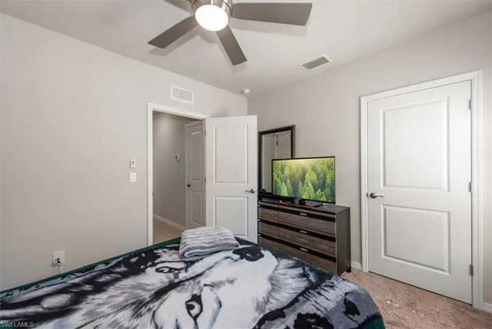 Carpeted bedroom featuring visible vents, baseboards, and a ceiling fan
