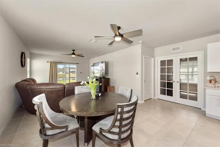 Dining area with french doors, light tile patterned flooring, a ceiling fan, and visible vents