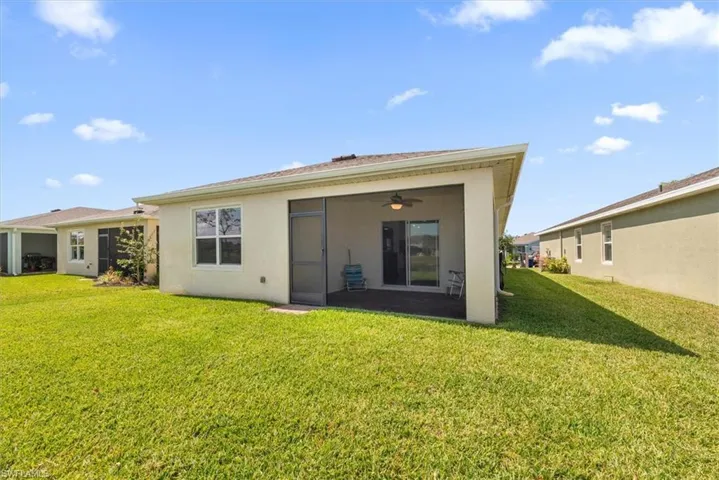 Back of property with a yard, stucco siding, and a ceiling fan