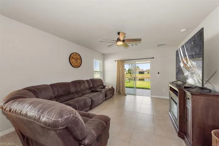 Living area featuring baseboards, light tile patterned floors, ceiling fan, and visible vents