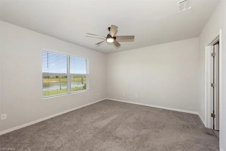 Unfurnished bedroom with carpet floors, baseboards, ceiling fan, and visible vents