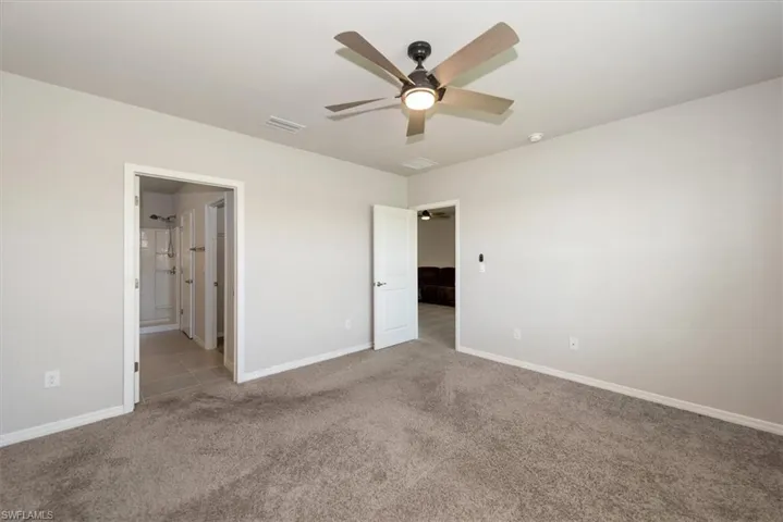 Unfurnished bedroom featuring connected bathroom, a ceiling fan, visible vents, carpet flooring, and baseboards