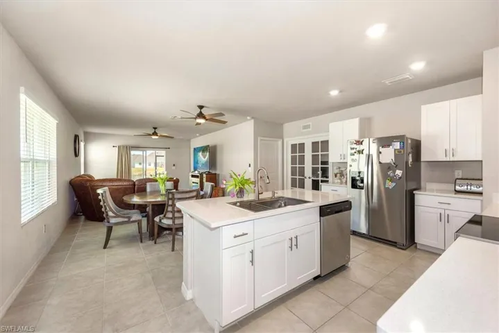 Kitchen with white cabinets, a kitchen island with sink, light tile patterned flooring, a sink, and stainless steel appliances