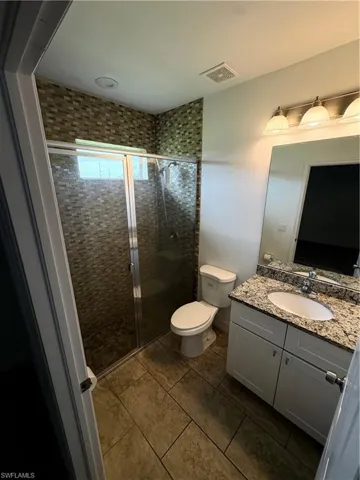 Walk-in shower with mosaic tile surround, glass enclosure, and shower head