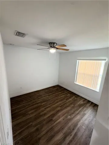 Wood-finish flooring with white walls and a ceiling fan
