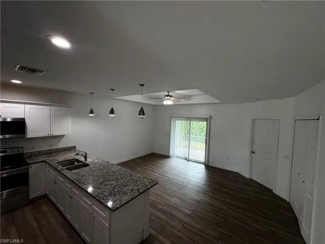 Kitchen island with granite countertop, white cabinetry, wood-finish flooring, recessed lighting, and a ceiling fan