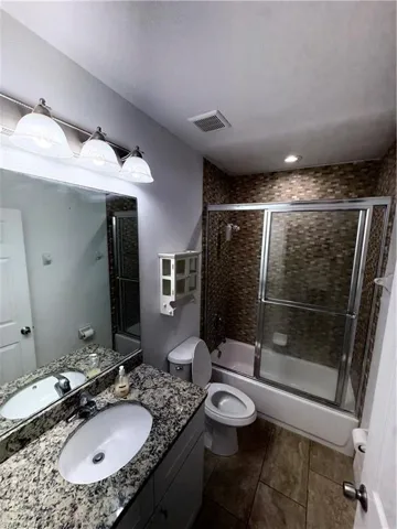 Bathroom featuring a vanity with an oval sink, speckled countertop, and overhead light fixture