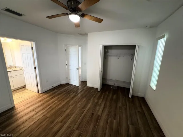 Wood-finish flooring, white painted walls, and a ceiling fan with integrated lighting