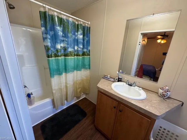 Bathroom with hardwood / wood-style flooring, shower / tub combo with curtain, vanity, and ceiling fan