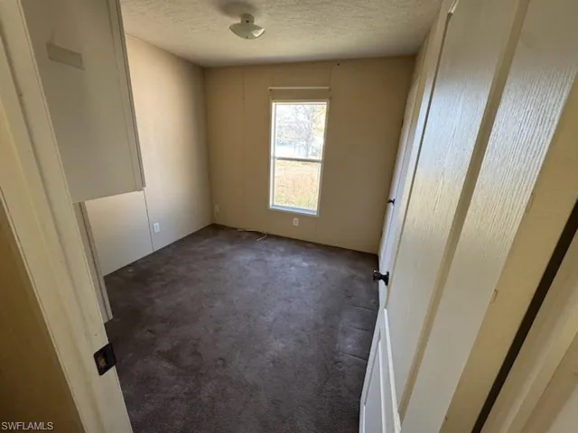 Spare room with dark carpet and a textured ceiling