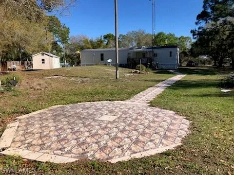 Back of property featuring a yard, a patio, and a storage unit