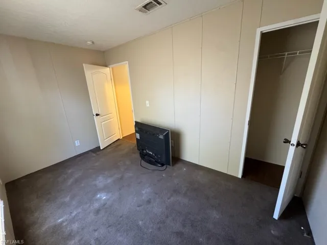 Unfurnished bedroom featuring a textured ceiling and dark colored carpet