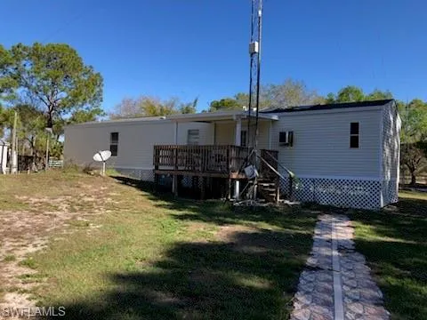 Back of house featuring a lawn and a deck