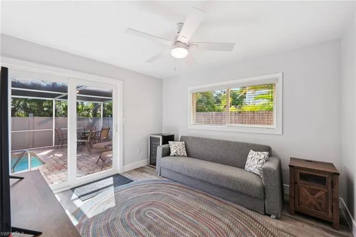 Living room featuring a sunroom, wood finished floors, and ceiling fan