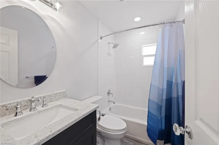 Bathroom with vanity, shower / bathtub combination with curtain, and recessed lighting