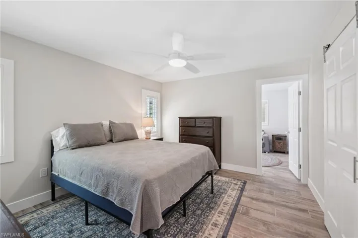 Bedroom with light wood-style floors, a ceiling fan, and ensuite bathroom