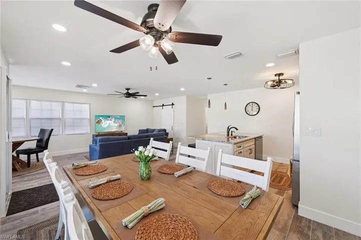 Dining space featuring a barn door, wood finished floors, recessed lighting, and a ceiling fan