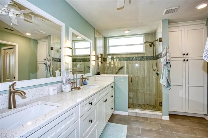 Bathroom featuring tile patterned flooring, vanity, ceiling fan, and a shower with shower door