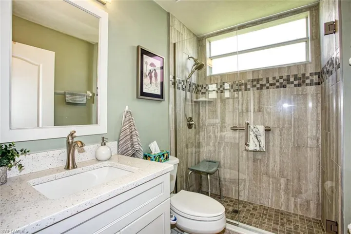 Bathroom with a shower with shower door, vanity, and toilet