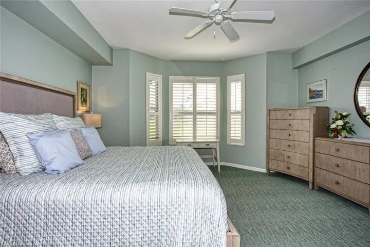 Bedroom with ceiling fan and dark colored carpet