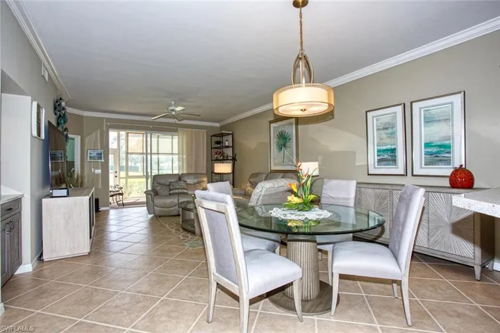 Tiled dining area with ceiling fan and ornamental molding