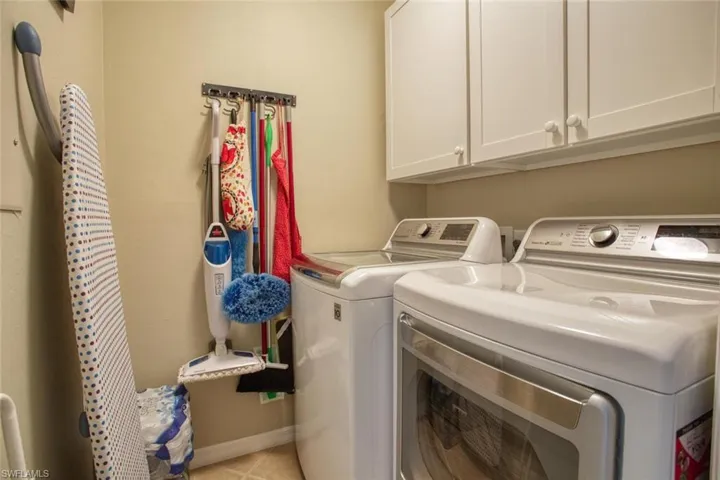 Laundry room featuring cabinets, washing machine and dryer, and light tile patterned floors