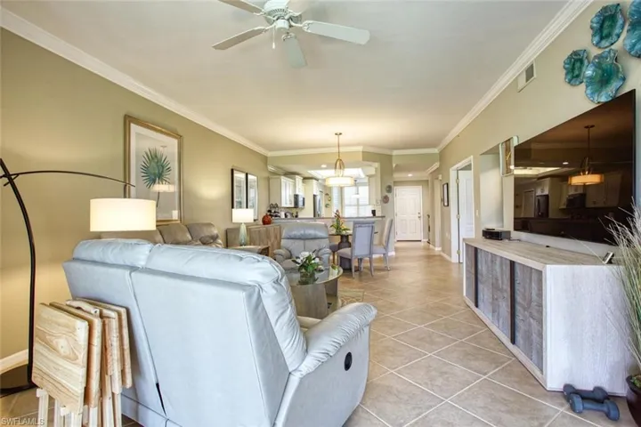 Tiled living room with ceiling fan and crown molding